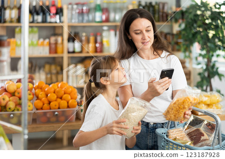 Mother and daughter checks expiration date of cornflakes and oat flakes - scans QR code on label Mother and daughter checks expiration date of cornflakes and oat flakes - scans QR code on label 123187928