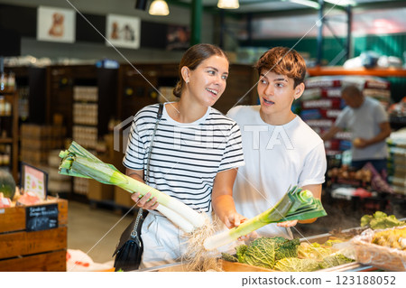 Young woman and young guy choosing leeks in grocery store 123188052