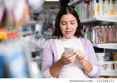 Young woman is choosing new conditioner in hair care store 123188171