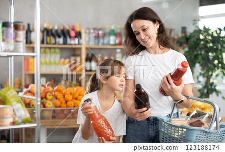 Mother and daughter choose tasty juice together in grocery section of supermarket 123188174