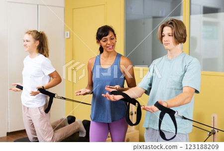 Teens doing pilates exercises with trainer 123188209