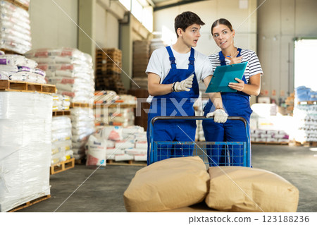 Girl check papers invoices together with guy employee and revise availability of goods in stock Girl check papers invoices together with guy employee and revise availability of goods in stock 123188236