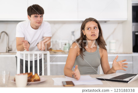 Young guy quarrels with young woman working at laptop Young guy quarrels with young woman working at laptop 123188338