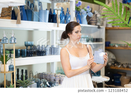 Woman examining blue and white porcelain jar in home decor store Woman examining blue and white porcelain jar in home decor store 123188452