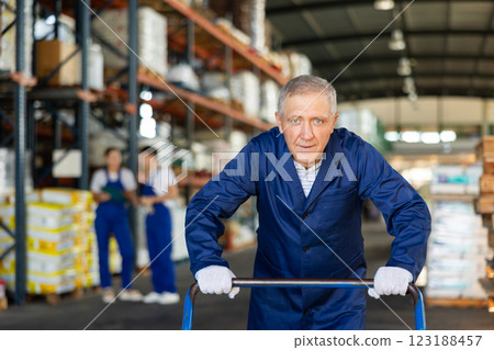 Elderly loader man pushing cart in warehouse Elderly loader man pushing cart in warehouse 123188457