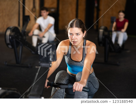 Focused girl works out with rowing machine during class at fitness club 123188540