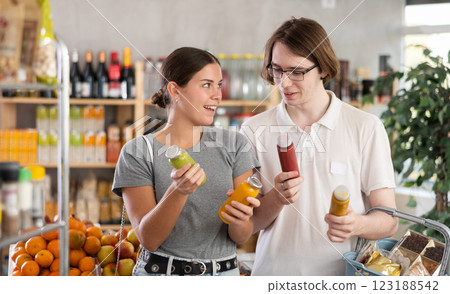 Youth girl and guy friends hold packages bottles and choose consider smoothie in store 123188542