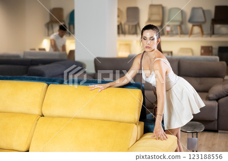 Female standing near sofa in the furniture store before buying 123188556