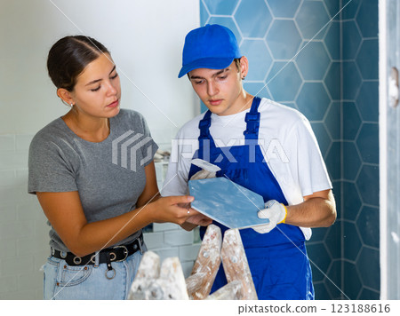 Builder discussing tiles with female owner of apartment being renovated Builder discussing tiles with female owner of apartment being renovated 123188616