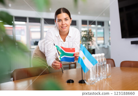 Preparing for business presentation - secretary places flags of Argentina and South Africa on negotiating table 123188660