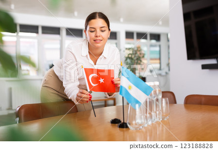 Positive young woman putting little flag of Turkey on table next to the flag of Argentina 123188828