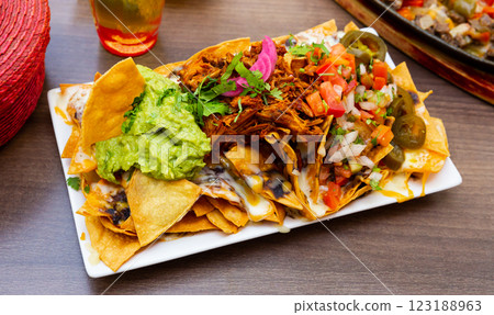 Nachos with meat, vegetables and sauces 123188963