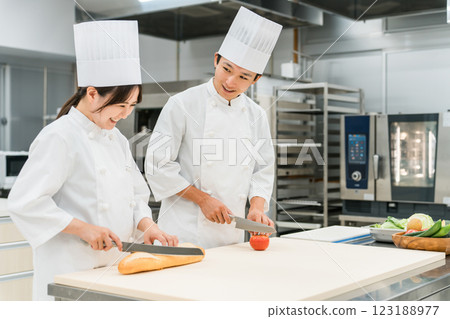 Male and female staff in chef coats preparing food in the kitchen (chefs, chefs, fresh market, food processing) 123188977