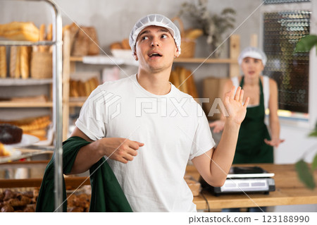 Dismissive young bakery worker ignoring coworker complaints Dismissive young bakery worker ignoring coworker complaints 123188990