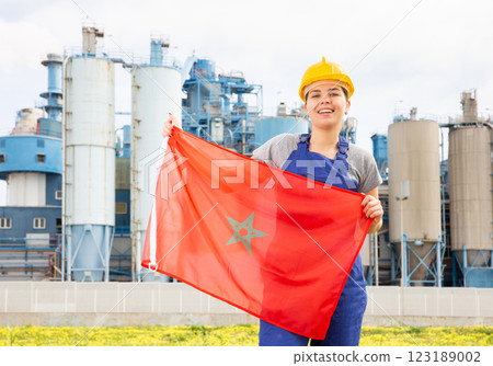 Happy girl in work clothes and hardhat with flag of morocco standing in front of industrial scenery Happy girl in work clothes and hardhat with flag of morocco standing in front of industrial scenery 123189002