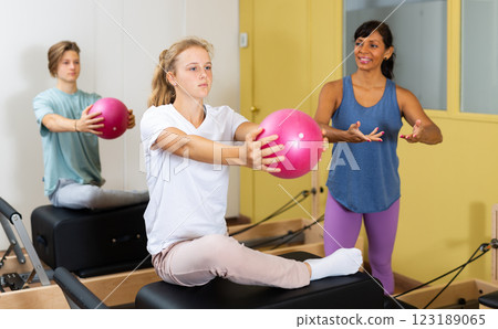 Pilates instructor shows girl how to exercise with ball Pilates instructor shows girl how to exercise with ball 123189065