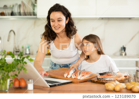 Happy mother and her daughter preparing salmon in the kitchen 123189070