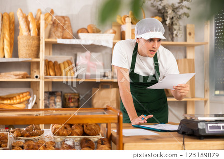 Surprised bakery worker reviewing unexpected order details 123189079