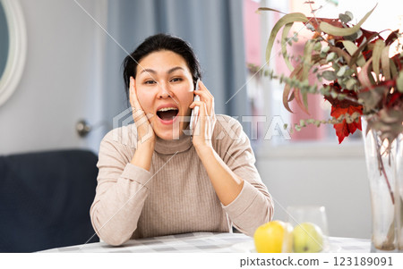 Positive asian woman communicates with someone on mobile phone 123189091