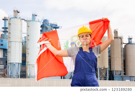 Worried girl in work clothes and hardhat with flag of peru standing in front of industrial scenery 123189280