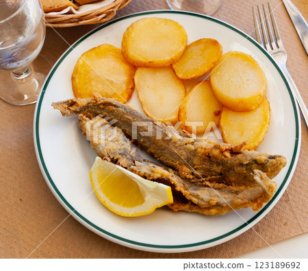 Fried hake served with boiled potatoes and lemon Fried hake served with boiled potatoes and lemon 123189692