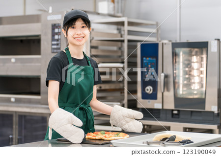 Female chef taking pizza out of the oven Female chef taking pizza out of the oven 123190049