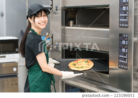 Female chef taking pizza out of the oven 123190051