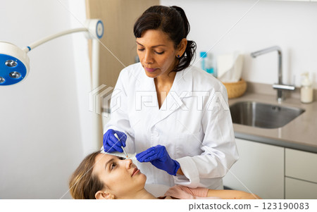 Cosmetologist using pencil for marking skin of patient 123190083
