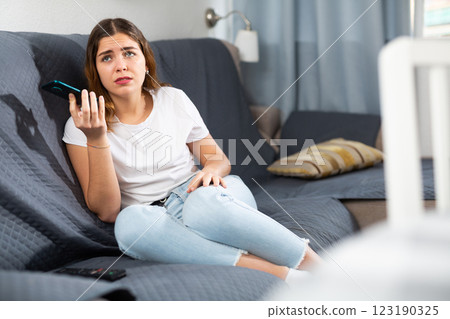 Disappointed woman talking on phone at home Disappointed woman talking on phone at home 123190325