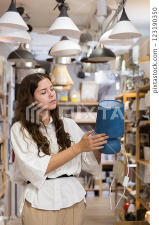 Woman is choosing new table lamp for her home in store. 123190350