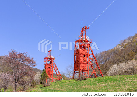 A shaft hoisting machine stands tall in the Coal Mine Memorial Forest Park, where kobushi trees bloom, in Bibai City, Hokkaido [May] 123191019