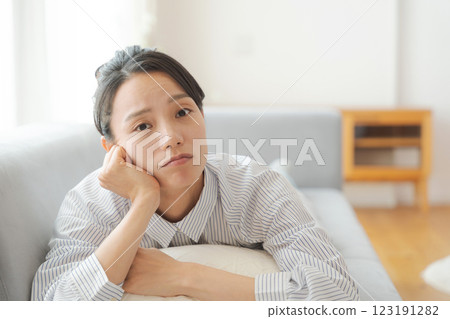 一個女人躺在沙發上,表情憂慮 一個女人躺在沙發上,表情憂慮 123191282