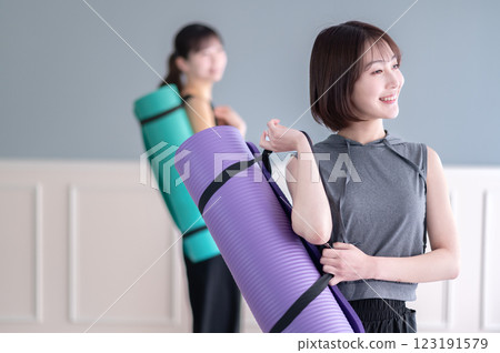 Smiling young woman with yoga mat Smiling young woman with yoga mat 123191579