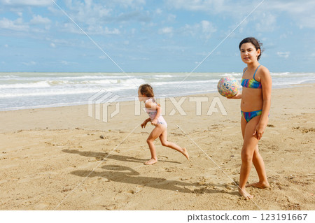 two girls in the swimsuit standing on the beach playing with ball two girls in the swimsuit standing on the beach playing with ball 123191667