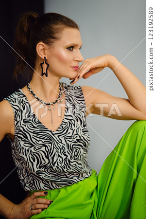 Beautiful woman displays a striking look with a zebra print top and bright green pants 123192589