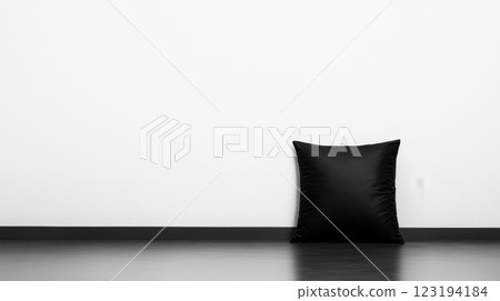 Soft black pillow resting on a minimalist floor against white wall 123194184