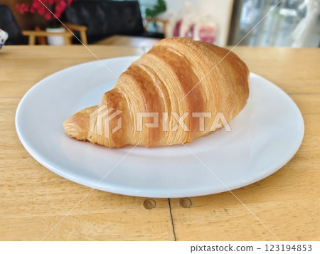 A croissant on white dish on table. A croissant on white dish on table. 123194853