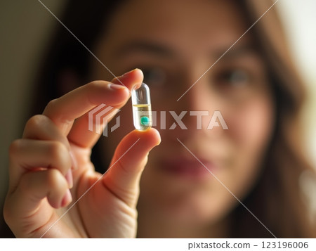 Healthcare and Wellness Lifestyle Close-up of Hand Holding  Supplement Capsule, pill with Soft Focus Portrait in Natural Light  123196006