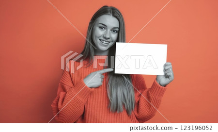 Cheerful Young Woman in Knitted Sweater Pointing at Blank Card Against Solid Background - Mockup Template for Advertisement or Announcement 123196052
