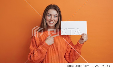 Cheerful Young Woman in Knitted Sweater Pointing at Blank Card Against Solid Background - Mockup Template for Advertisement or Announcement 123196055