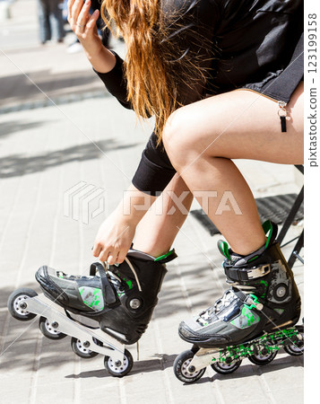 Young woman putting roller skates on Young woman putting roller skates on 123199158