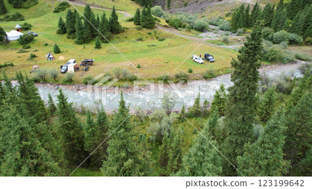 Tourists camping near river in green valley with yurts and cars Tourists camping near river in green valley with yurts and cars 123199642