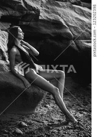 Black and white artistic portrait of a woman in a swimsuit, posing against a rocky landscape Black and white artistic portrait of a woman in a swimsuit, posing against a rocky landscape 123202398