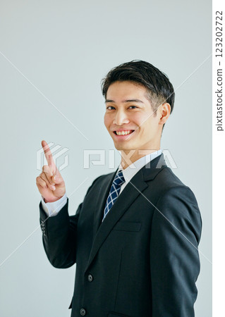 Young man pointing his index finger up 123202722
