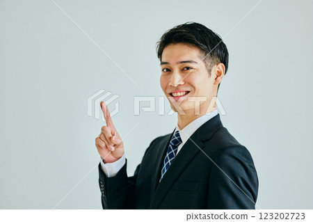 Young man pointing his index finger up 123202723