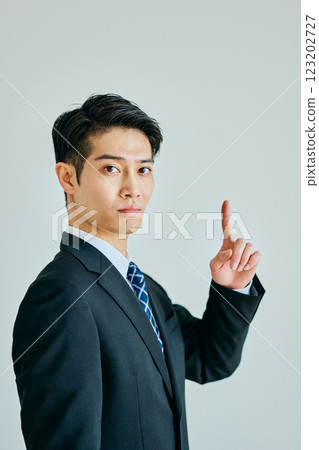 Young man pointing his index finger up 123202727