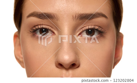 Close-up of young woman's eyes with well-defined, well-groomed eyebrows and long lashes against white studio background. Close-up of young woman's eyes with well-defined, well-groomed eyebrows and long lashes against white studio background. 123202804