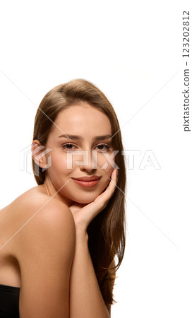 Portrait of young pretty woman with soft smile, looking at camera, resting face on hand against white studio background. Portrait of young pretty woman with soft smile, looking at camera, resting face on hand against white studio background. 123202812