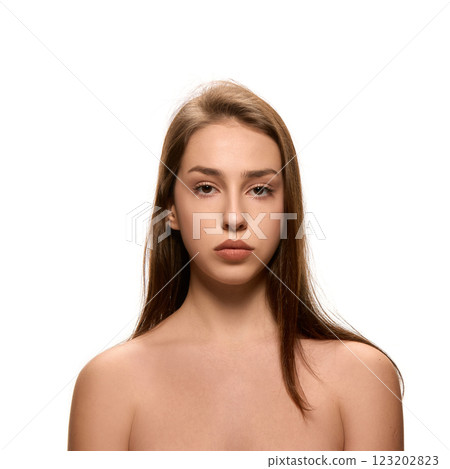 Portrait of young woman with natural makeup looking straight with calm expression at camera against white studio background. Portrait of young woman with natural makeup looking straight with calm expression at camera against white studio background. 123202823