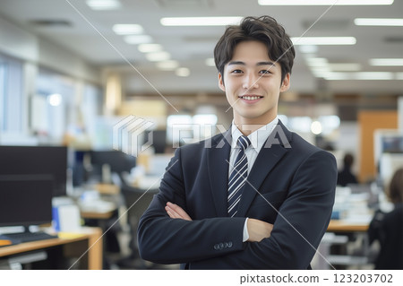 A young male businessman standing with his arms folded and a confident look A young male businessman standing with his arms folded and a confident look 123203702